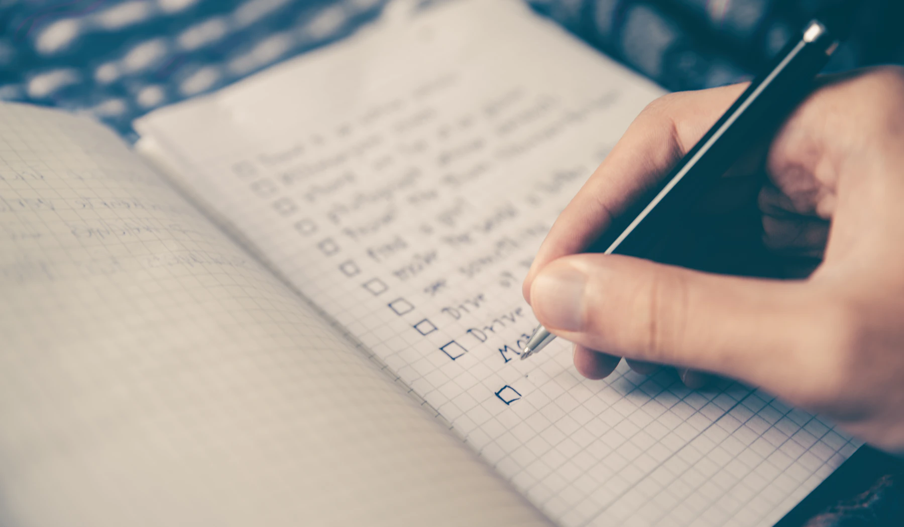 A person writing a checklist in a notebook